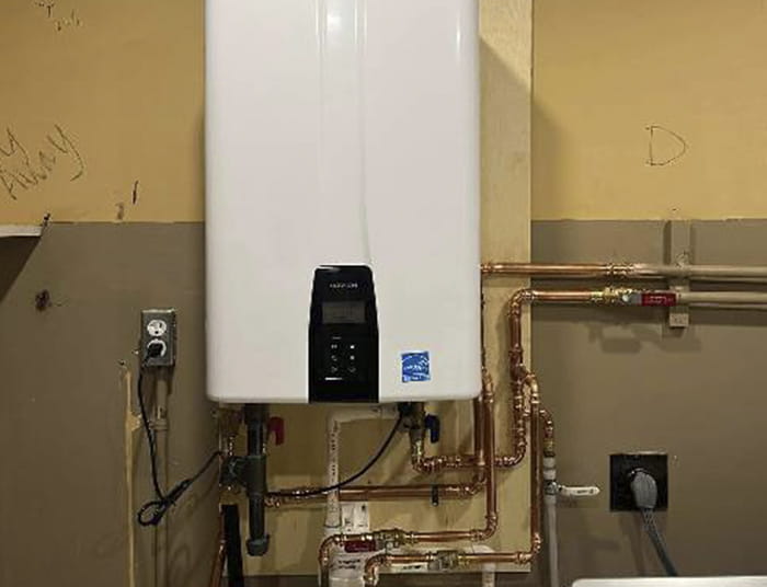 Wall-mounted tankless water heater connected to copper piping.